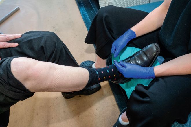 Mantelzorger helpt iemand met veters strikken van schoen