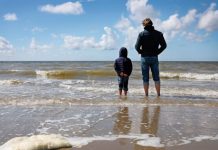 Multimethodisch werken Werken met rouw en verlies man en kind staan met hun voeten in de zee en kijken naar de horizon