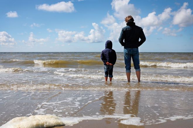 Multimethodisch werken Werken met rouw en verlies man en kind staan met hun voeten in de zee en kijken naar de horizon