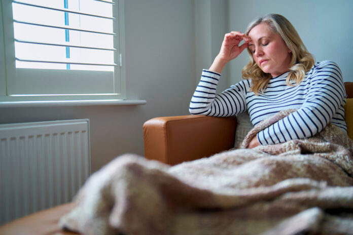 Vrouwelijke economische daklozen Vrouw op de bank onder een dekentje, kijkt zorgelijk